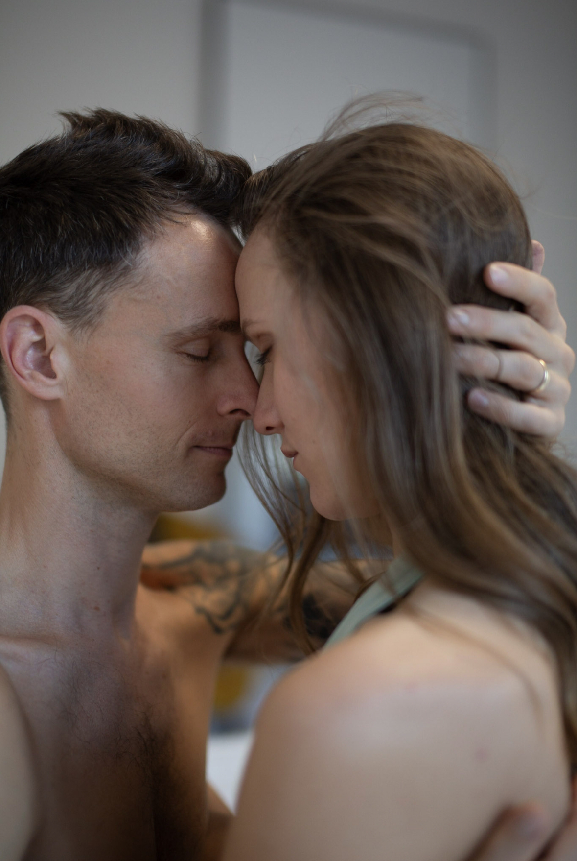 A couple resting forehead to forehead in quiet presence.