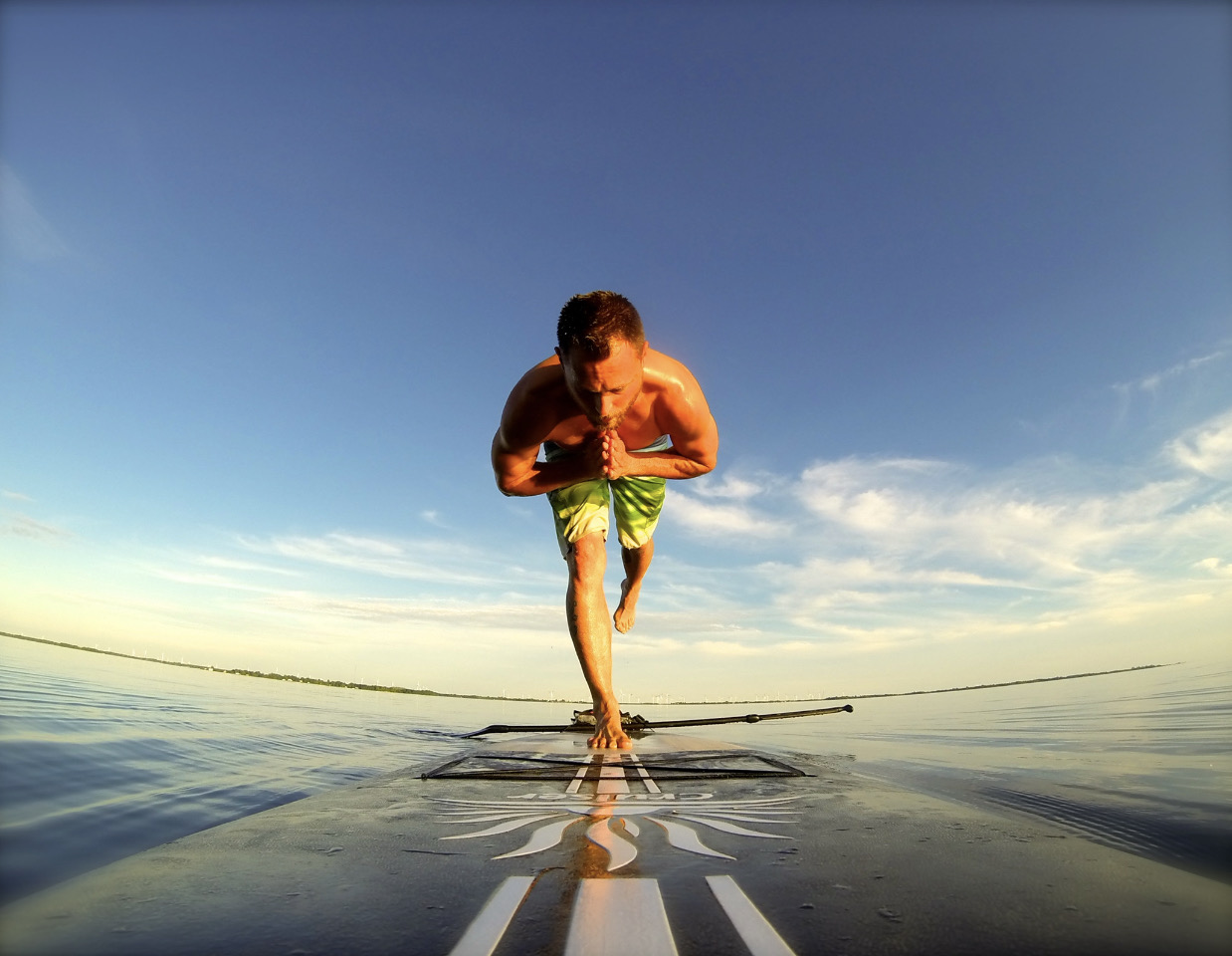 Jonathan in standing balance on a paddleboard at golden hour